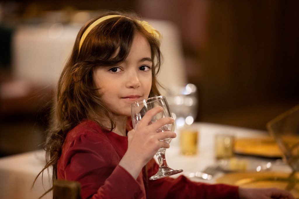 Young girl drinking water at a dining table