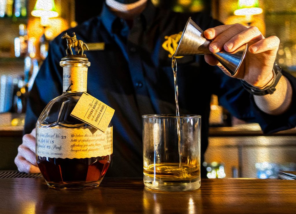bartender pouring a glass of bourbon