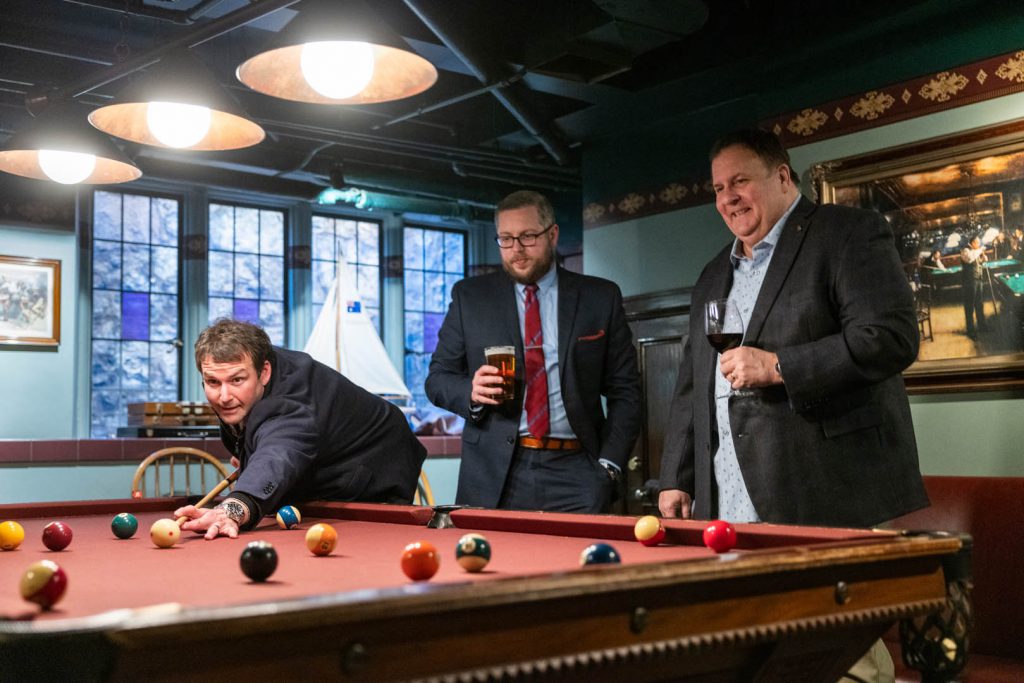 group of men with drinks playing pool